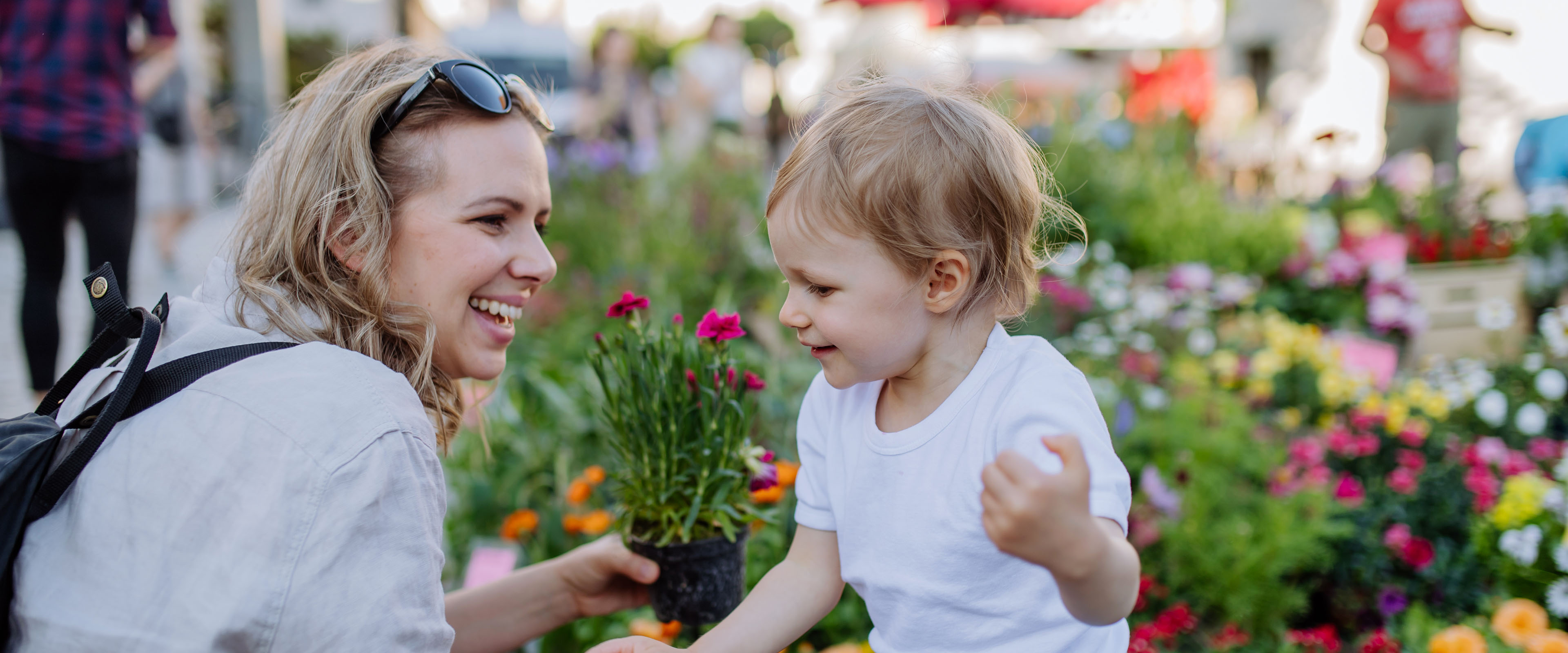 Zwei Personen lächeln, während sie gemeinsam an einer Glaswand mit Stift und Haftnotizen arbeiten.